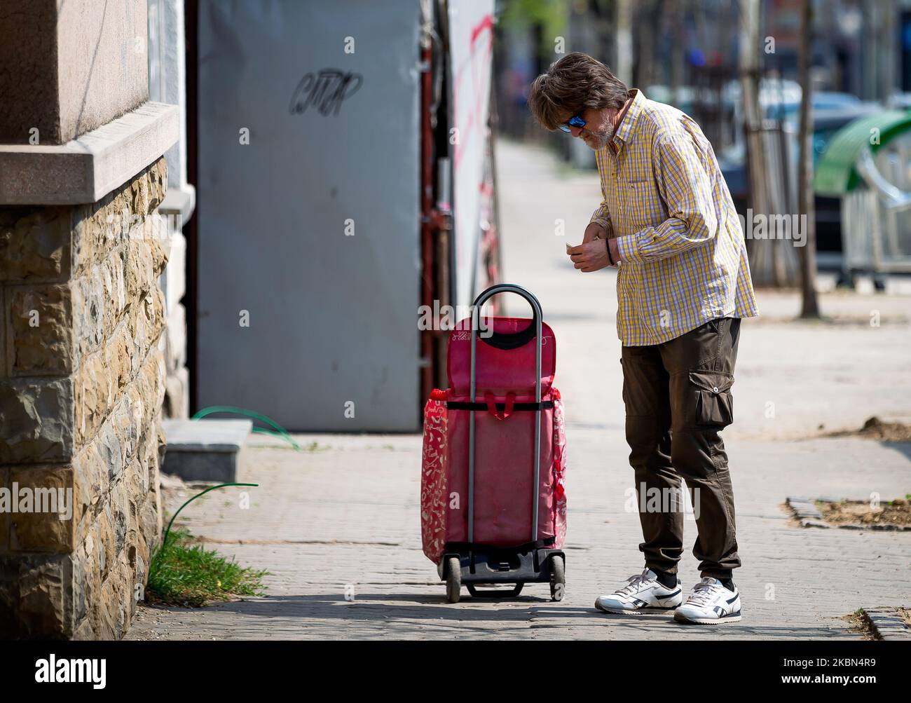 Un vecchio sulla via del ritorno dal mercato si ferma per contare i soldi dopo la riapertura di parrucchieri, palestre, mercati e parchi durante la malattia del coronavirus (COVID-19) a Belgrado, in Serbia, il 30 aprile 2020. Il presidente serbo Aleksandar Vucic aveva dichiarato lo stato di emergenza per fermare la diffusione del coronavirus. Anche il governo ha vietato a tutti gli oltre i 65 anni di lasciare le loro case. A seguito del calo del numero di pazienti con coronavirus il governo di questa settimana permette la riapertura di parrucchieri, palestre, mercati e parchi. (Foto di Nikola Krstic/NurPhoto) Foto Stock