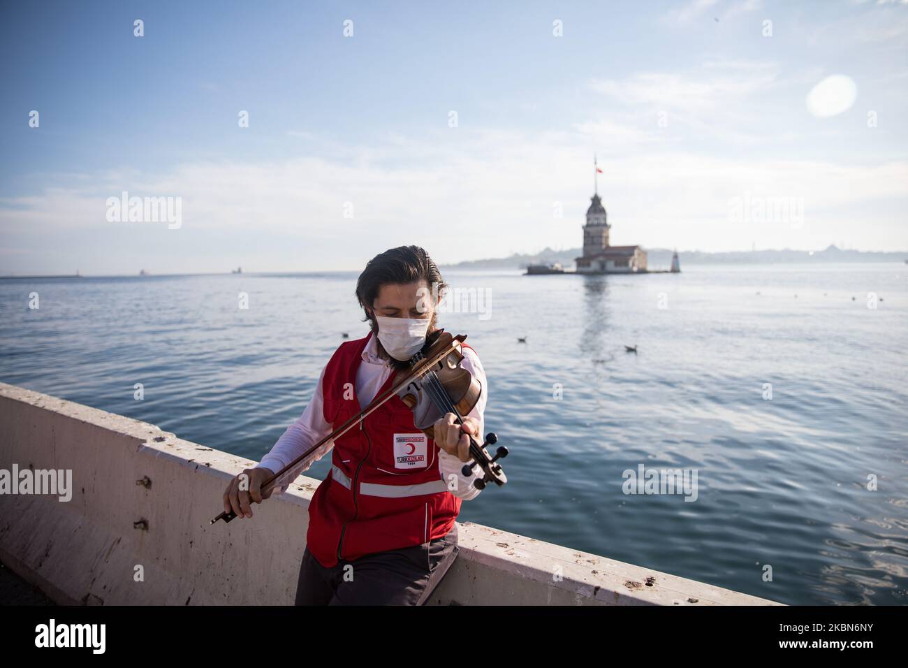 Kä±zÄ±Lay (servizio di aiuto umanitario in Turchia) operaio suona violino in una strada costiera vuota intorno alla Torre di Maiden a Istanbul, Turchia il 01 maggio 2020. La Turchia ha adottato una serie di misure per prevenire la diffusione del virus, tra cui la chiusura di scuole, ristoranti e altri spazi pubblici. Ci sono anche coprifuoco tutto il giorno del fine settimana in 31 città tra cui Istanbul, con un blocco di tre giorni dal 1 maggio, una festa pubblica. (Foto di CEM TekkeÅŸinoÄŸlu/NurPhoto) Foto Stock