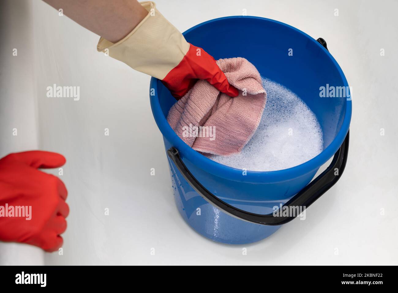 la mano toglie uno straccio bagnato da un secchio d'acqua Foto Stock