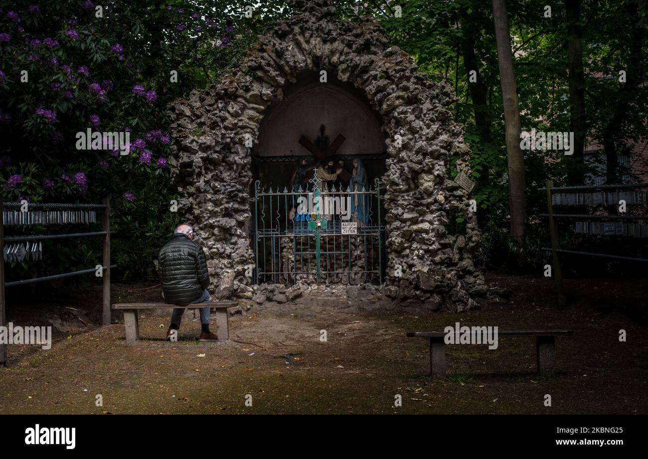 Un credente anziano prega davanti alla grotta di Lourdes a Oostakker - Belgio il 08 maggio 2020. Normalmente in maggio è molto occupato dentro e intorno al pellegrinaggio cite, onorando nostra Signora di Lourdes reputato avere proprietà curative. Attraverso la crisi della corona (COVID19) non si verificano eventi a causa di una stretta chiusura in Belgio per fermare la diffusione della pandemia COVID-19, causata dal nuovo coronavirus. Ai credenti è permesso camminare e pregare e accendere una candela nella basilica. La grotta di Lourdes è una replica della grotta originale a Lourdes in Francia. (Foto di Jonathan Raa/NurPhoto) Foto Stock