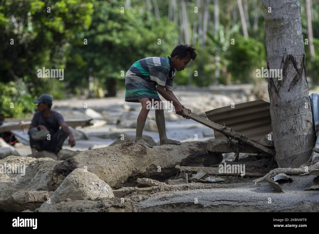 Un bambino raccoglie legno dalla sua casa che è stato perso in un'alluvione flash nel poi Village, distretto di South Dolo, Sigi Regency, Provincia Centrale di Sulawesi, Indonesia il 16 maggio 2020. Le alluvioni che hanno colpito il villaggio il 15 maggio 2020 notte, hanno causato 40 case gravemente danneggiate e 5 case sono state perse a causa di alluvioni accompagnate da rocce e fango. Il disastro di alluvione flash nella zona si è verificato ripetutamente e il governo locale prevede di trasferire più di 200 persone nel villaggio. (Foto di Basri Marzuki/NurPhoto) Foto Stock