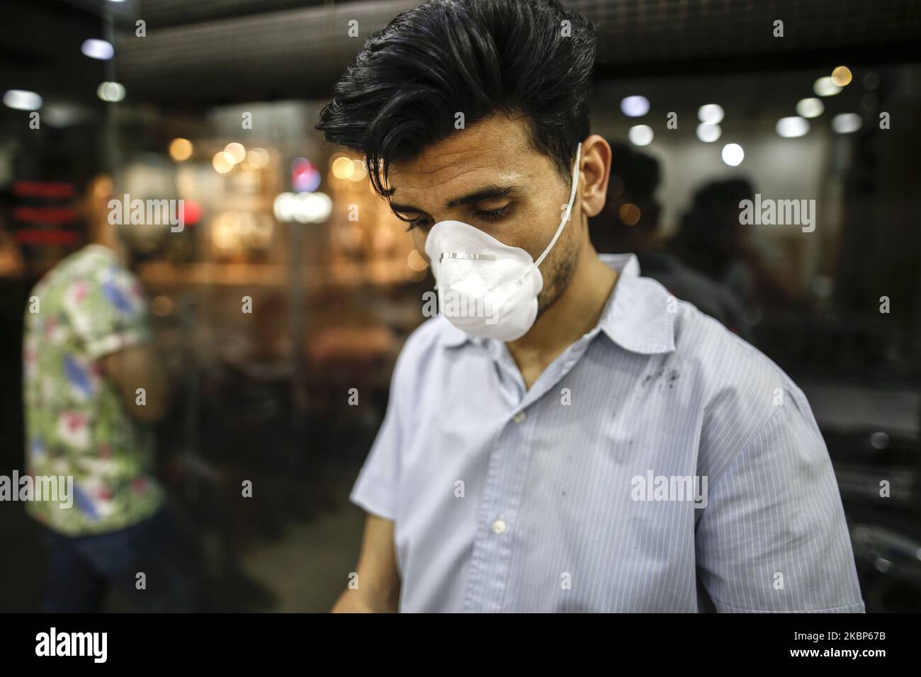 Indossando una maschera per proteggersi dal coronavirus, il barbiere Younis Abu-Aqrab, mentre i capelli di una giovinezza palestinese si tagliano nel suo salone a Gaza City, l'ultimo giorno del mese di festa del Ramadan alla preparazione di Eid al-Fitr, Il 23 maggio 2020, tra le preoccupazioni circa la diffusione della malattia di coronavirus (COVID-19) nella striscia di Gaza. Il Ministero della Salute palestinese di Gaza ha confermato che trentacinque nuovi casi di coronavirus che causano nella striscia di Gaza dal 19 al 21 maggio 2020. (Foto di Sameh Rahmi/NurPhoto) Foto Stock