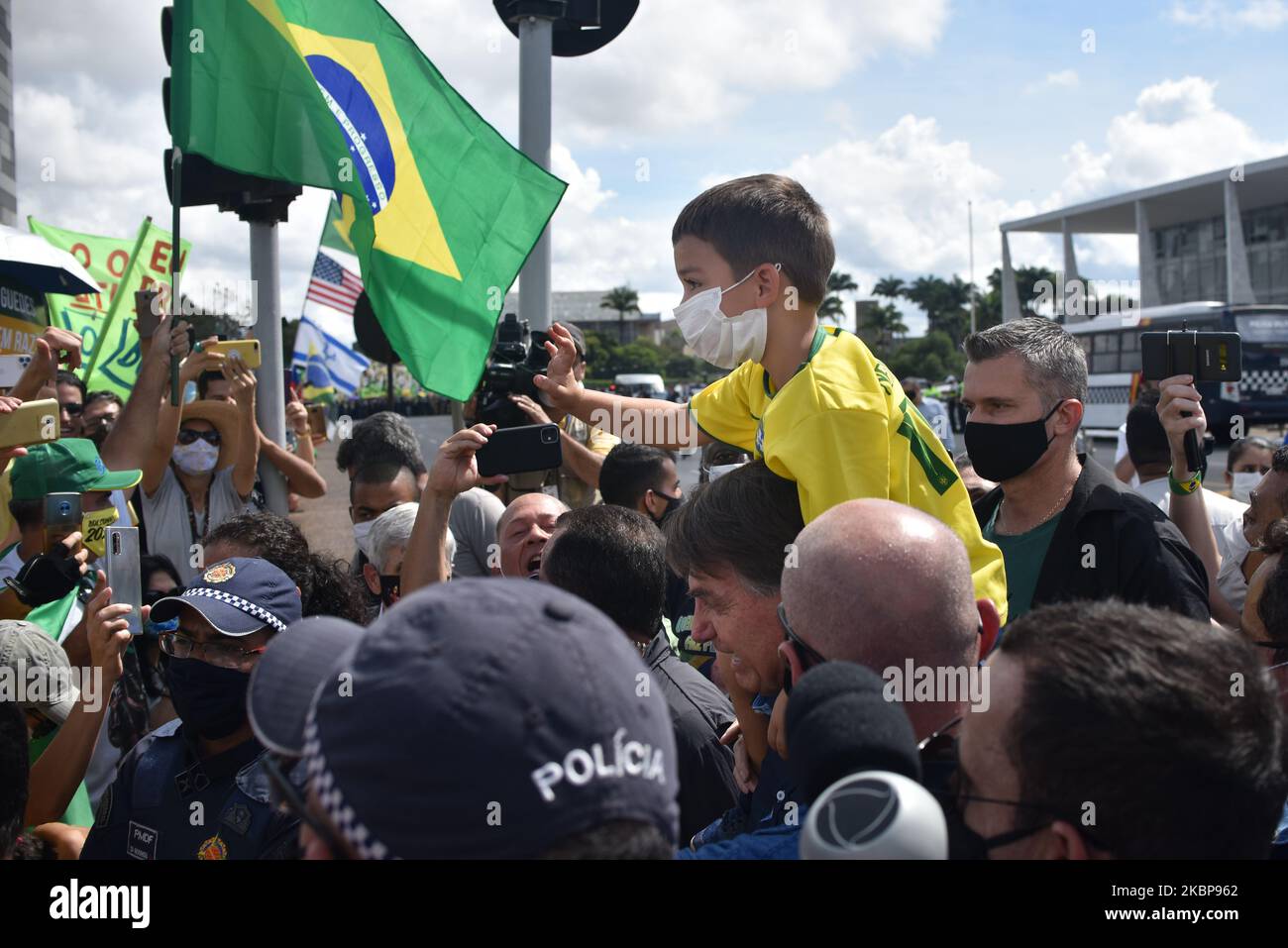 Senza maschera facciale, il presidente brasiliano Jair Bolsonaro porta un ragazzo sulle spalle mentre saluta i suoi sostenitori a Praca dos Três Poderes, di fronte al Palazzo Planalto durante una protesta contro le misure di isolamento sociale, contro la Corte Suprema e il Congresso Nazionale, in mezzo alla pandemia di Coronavirus (COVID-19), A Brasilia, Brasile , domenica 24 maggio, 2020. (Foto di Andre Borges/NurPhoto) Foto Stock