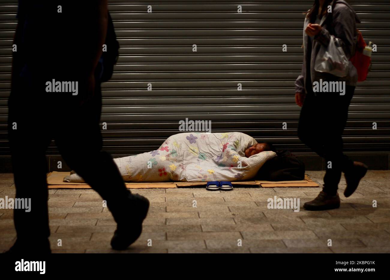 Una persona senzatetto maschile con una coperta si trova sul marciapiede fuori da una catena di negozi che vendono merci, a Ximen, Taipei City di Taiwan il 27 maggio 2020, come continua la malattia del coronavirus Covid-19 (Foto di Ceng Shou Yi/NurPhoto) Foto Stock