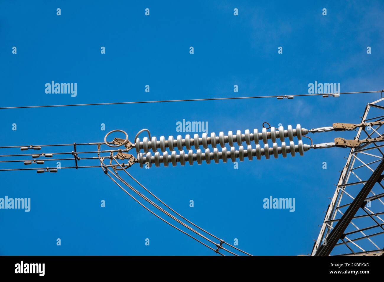 Primo piano dettagli di sezioni di un pilone elettrico ad alta tensione contro un cielo blu brillante Foto Stock