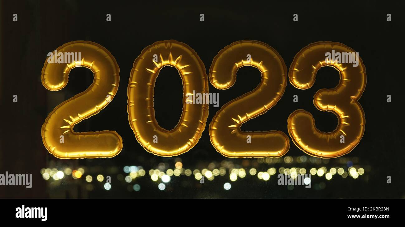 Palloncini gonfiabili d'oro numero 2023 sulla finestra sullo sfondo della città notturna, in luce al neon. Capodanno 2023, natale. Natale e Capodanno 2023. Foto Stock