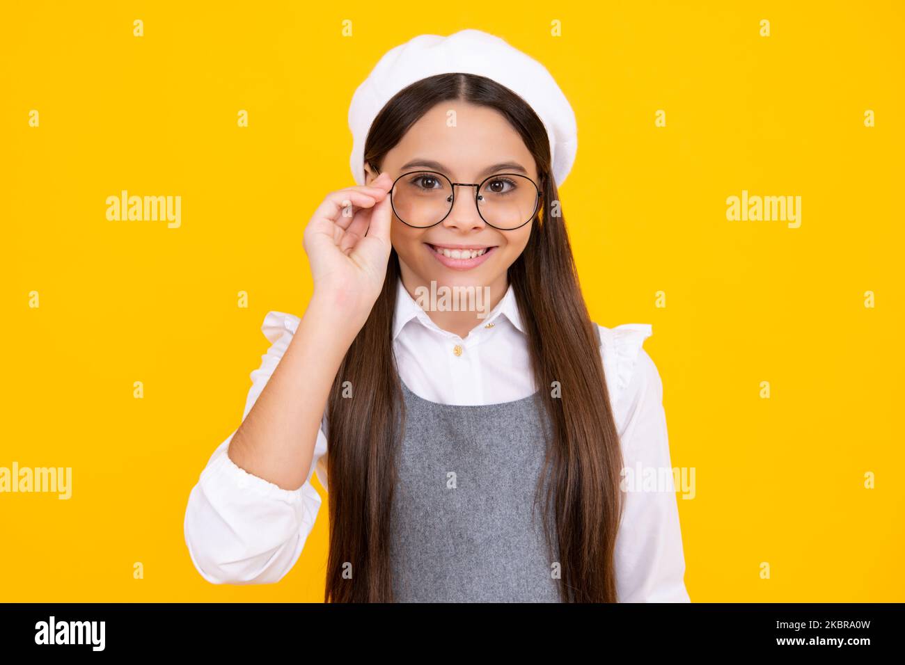 Tennager ragazza bambino indossare occhiali guardando la fotocamera con fiducia su sfondo giallo, copia spazio. Il bambino ottiene la vista. Faccia felice, positivo e. Foto Stock