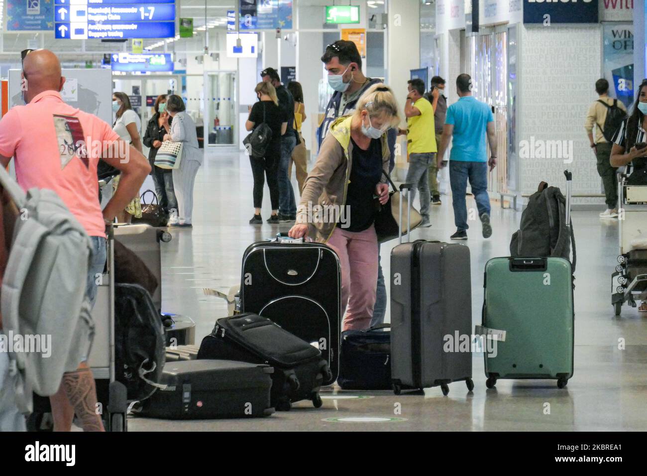 Passeggeri visti con le maschere facciali obbligatorie all'aeroporto internazionale ATH LGAV di Atene, in Grecia, il 18 giugno 2020, dopo la quarantena di Coronavirus e le restrizioni di viaggio. I passeggeri che indossano maschere e guanti, utilizzano disinfettanti per le mani come misura preventiva contro la diffusione della pandemia COVID-19. La Grecia e l'Europa hanno chiuso a lungo le frontiere per le persone al di fuori dell'Europa e della zona Schengen, ma la Grecia ha iniziato a revocare il divieto di circolazione dal 15 giugno 2020 per i paesi della zona Schengen e il 1 luglio 2020 si arriverà a un maggiore allentamento. I passeggeri in arrivo sono soggetti al decor Foto Stock