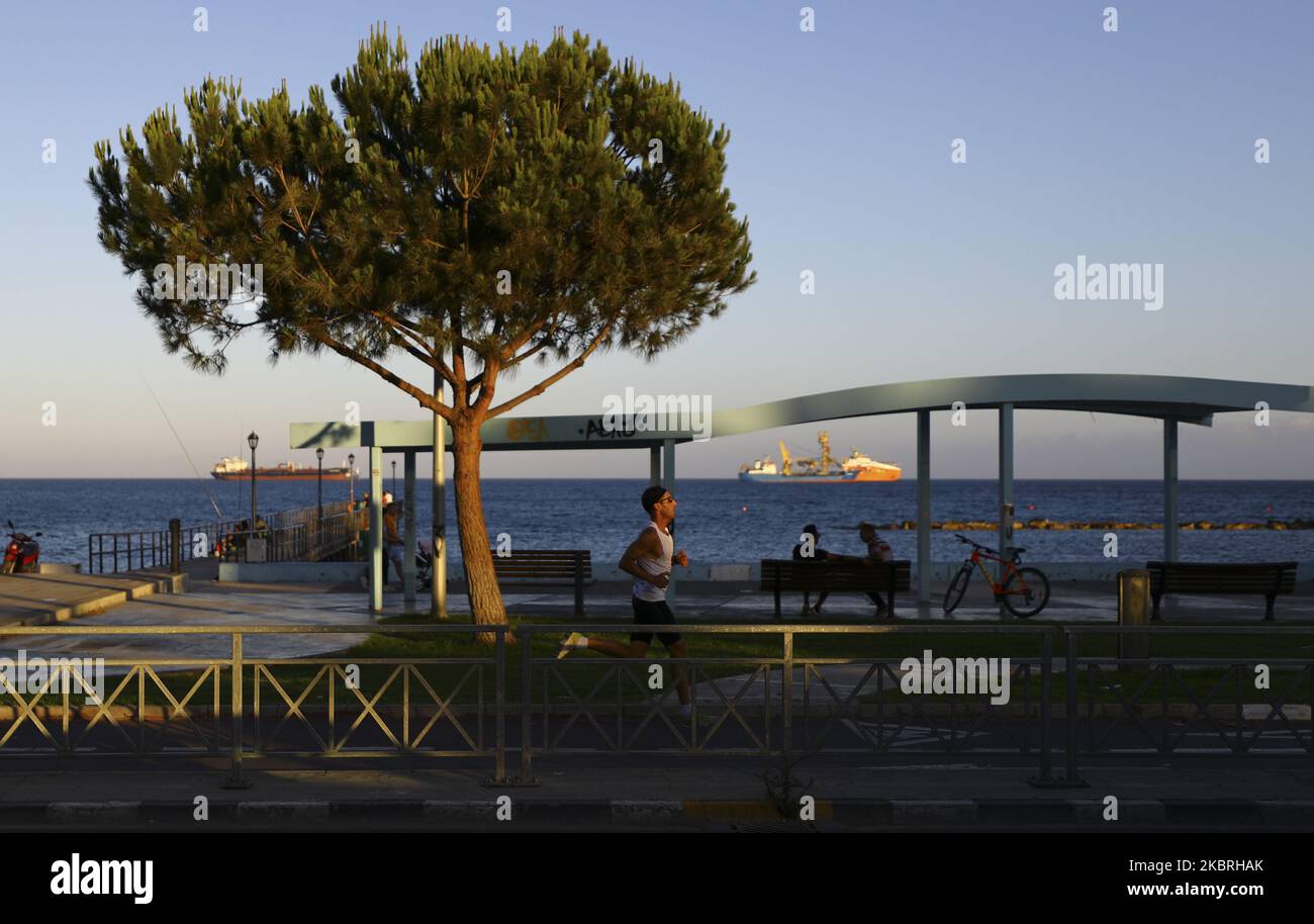 Sunset illuminates a man who plays sports on the waterfront. Limassol, Cyprus, Tuesday, June 23, 2020 The Ministry of Health of Cyprus from June 24 repeals the rule limiting meetings to a maximum of 10 people. Thus, since June 24, the maximum allowed number of participants for meetings in closed rooms is 75 people, for open rooms - 150 people. This rule applies to wedding ceremonies, christenings, concerts, festivals, private gatherings in houses (in this case, the owners of the house are also considered participants) and to all other forms of mass gatherings. Larger and more numerous events a Foto Stock