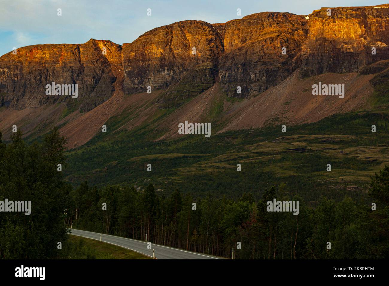 Strada grigia sulle montagne norvegesi nella notte di sole Foto Stock