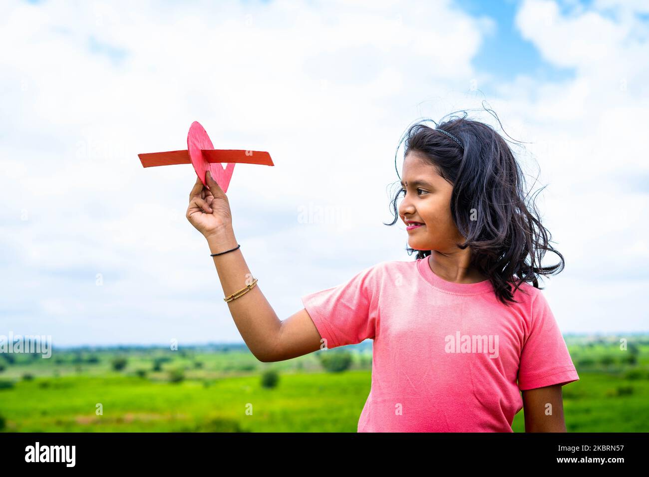 Ragazza giovane sorridente felice che gioca con aereo di cartone in montagna - concetto di sogno pilota di infanzia, libertà e aspirazioni Foto Stock