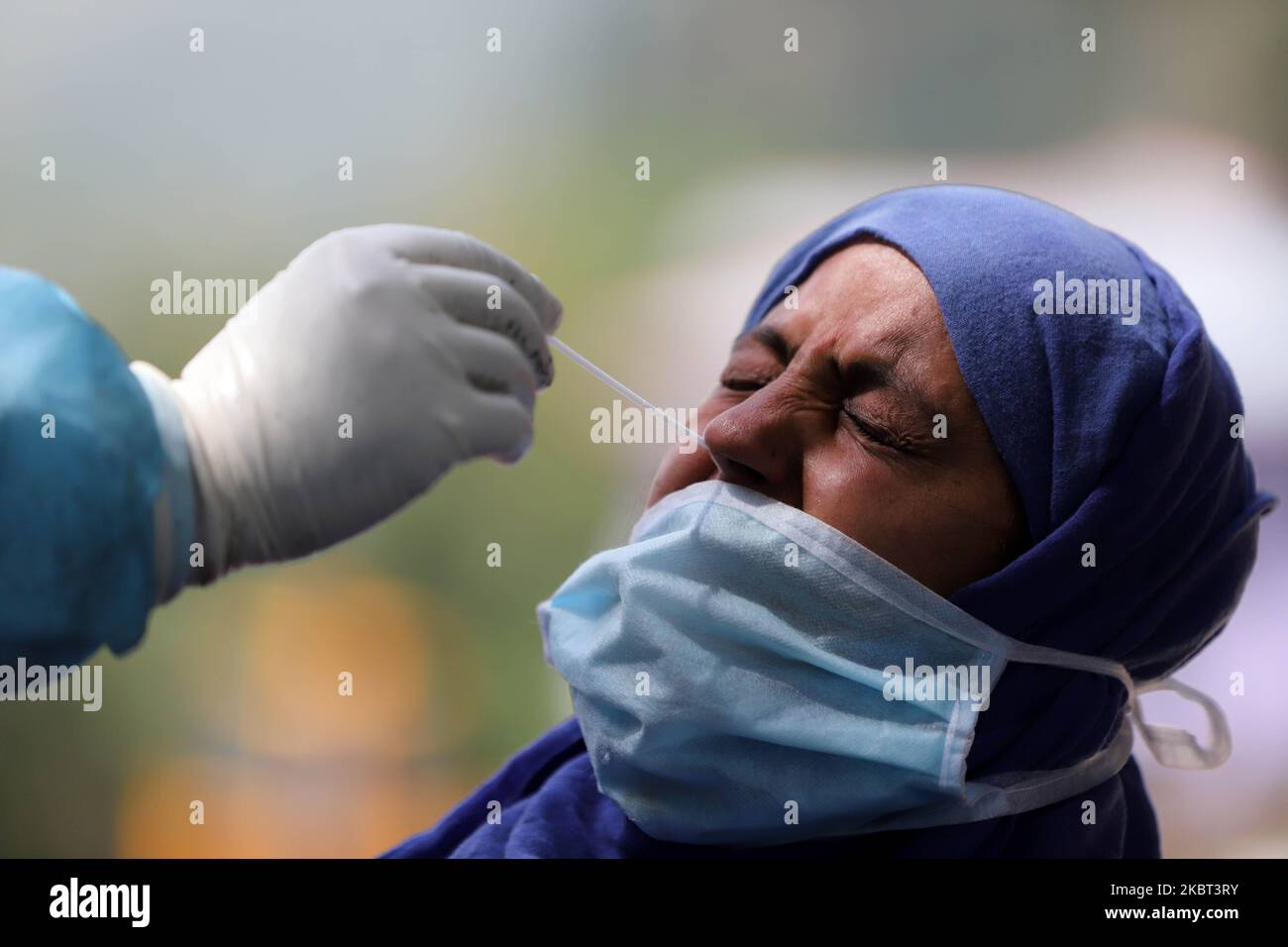 Un funzionario sanitario in tute DPI raccoglie un campione di tampone da un individuo per il test COVID-19 (coronavirus) nel distretto di Baramulla, Jammu e Kashmir, India il 04 luglio 2020. Un team di esperti guidati dal medico di blocco Boniyar Dr. Pervaiz Masoodi, ha condotto test casuali nella zona sui gradini di accesso della gente. Le persone sono state informate in anticipo dal reparto di collaborare con il team medico e venire avanti per i test per la loro sicurezza. I lavoratori di Asha e altri medici di Boniyar Block hanno lavorato sodo per convincere le persone a un campionamento casuale. In occasione BMO Boniyar ha detto che loro Foto Stock