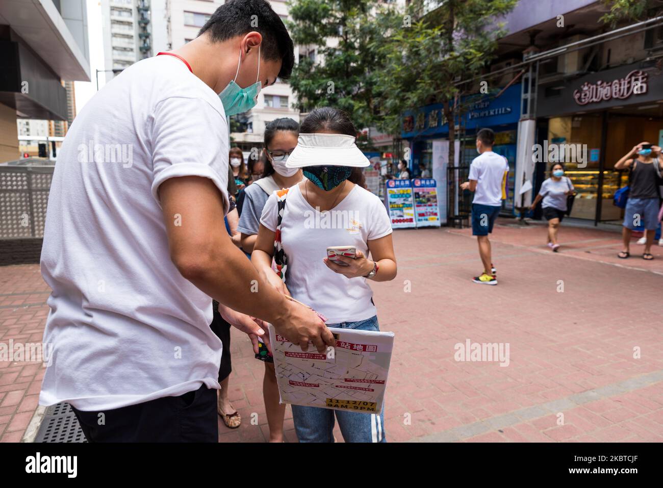 Un volontario aiuta un elettore a scansionare il codice QR richiesto per far contare il suo voto verso le primarie presso lo stand di voto di Whampoa a Hong Kong, Cina, il 11 luglio 2020. Il governo di Hong Kong li ha denunciati come una ''violazione'' della legge sulla sicurezza nazionale, e la polizia ha fatto irruzione negli uffici dell'impresa che organizzava la votazione la sera precedente la votazione, ritardando così l'inizio alle 12,00. (Foto di Marc Fernandes/NurPhoto) Foto Stock