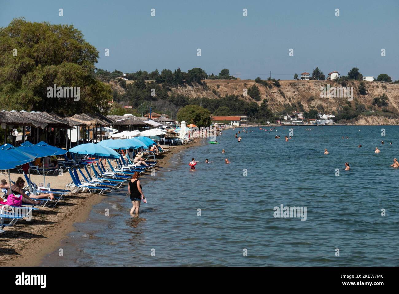 Vita quotidiana alla spiaggia sabbiosa di Agia Triada vicino a Salonicco in Grecia il 26 luglio 2020. AGIA Triada è una destinazione turistica estiva per i locali e i turisti stranieri per le vacanze soprattutto dai paesi balcanici. La spiaggia è premiata con la Bandiera Blu, ha tipico per le spiagge greche e il Mar Egeo, acqua di mare trasparente e cristallina, sabbia dorata e molte strutture turistiche come una strada pedonale lungomare accanto alla riva, docce gratuite ecc ci sono alberghi, taverne, ristoranti, Bar e bar sulla spiaggia nell'area, che e' ad appena pochi minuti di auto dall'Internazionale di Thessaloniki Foto Stock