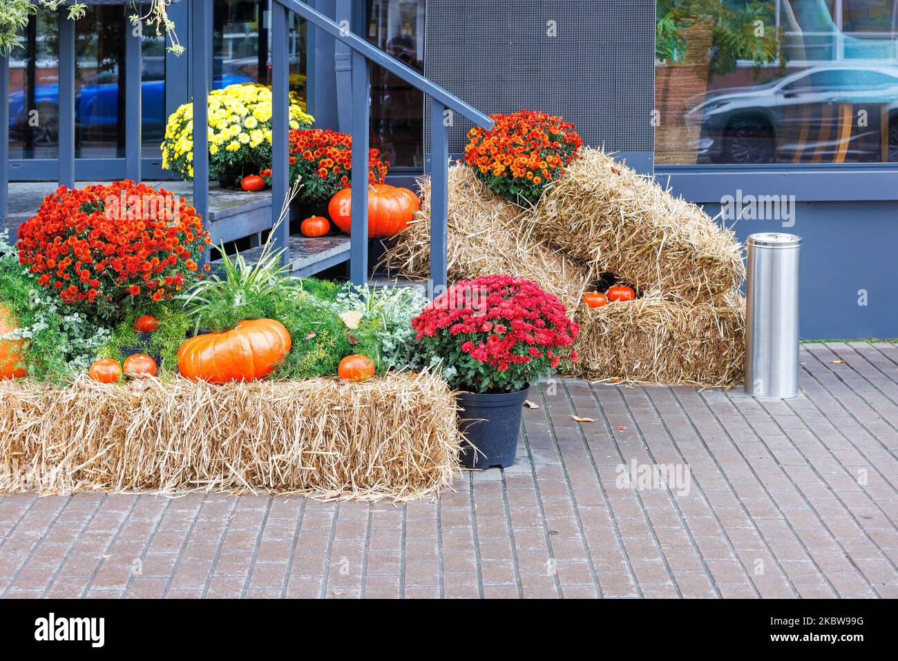 Sulle scale di legno di un caffè di strada di fronte all'entrata ci sono zucche, fiori e balle di paglia per la festa di Halloween. Foto Stock