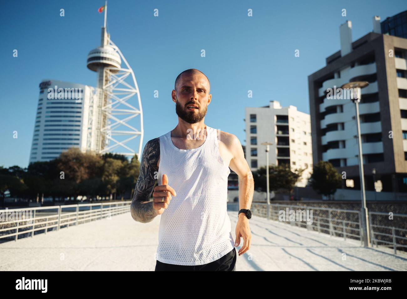 Male runner in Lisbon. Young bearded tattooed guy jogging outdoors, portrait of active man jogging on a sunny day Foto Stock