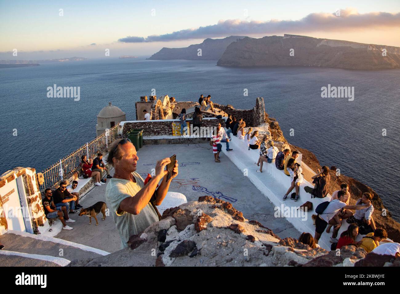 I turisti che si godono il tramonto incredibile a Oia, nell'isola del  vulcano di Santorini, nelle Cicladi, Mar Egeo, in Grecia. Sono raccolti in  un punto di vista sul vecchio castello tradizionale