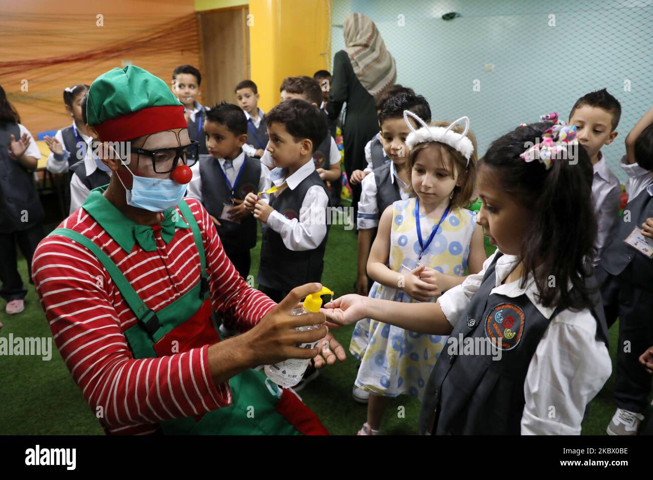 Un clown assunto da un asilo locale disinfetta le mani di uno studente durante una sessione di sensibilizzazione sulla malattia da coronavirus COVID-19 presso i locali di Gaza City il 10 agosto 2020, Come strutture educative nell'enclave palestinese riaperto per il nuovo anno accademico 2020-2021 a seguito di un allentamento delle restrizioni pandemiche. (Foto di Majdi Fathi/NurPhoto) Foto Stock