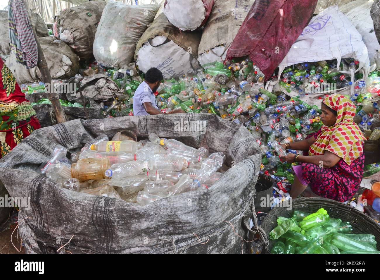 Le lavoratrici della donna ordinano le bottiglie di polietilentereftalato (PET) in una fabbrica di riciclaggio a Dhaka, Bangladesh, il 12 agosto 2020. Negli ultimi due anni il riciclaggio delle bottiglie di plastica è diventato un'attività in crescita e contribuisce alla tutela dell'ambiente. Secondo la BPFMEA (Bangladesh PET Flakes Manufacturers and Exporters Association), il Bangladesh esporta in media circa 30.000 tonnellate di scaglie di PET in bottiglia principalmente verso Cina, Corea del Sud e Taiwan per un valore di $14 milioni di dollari l'anno. (Foto di Mamunur Rashid/NurPhoto) Foto Stock
