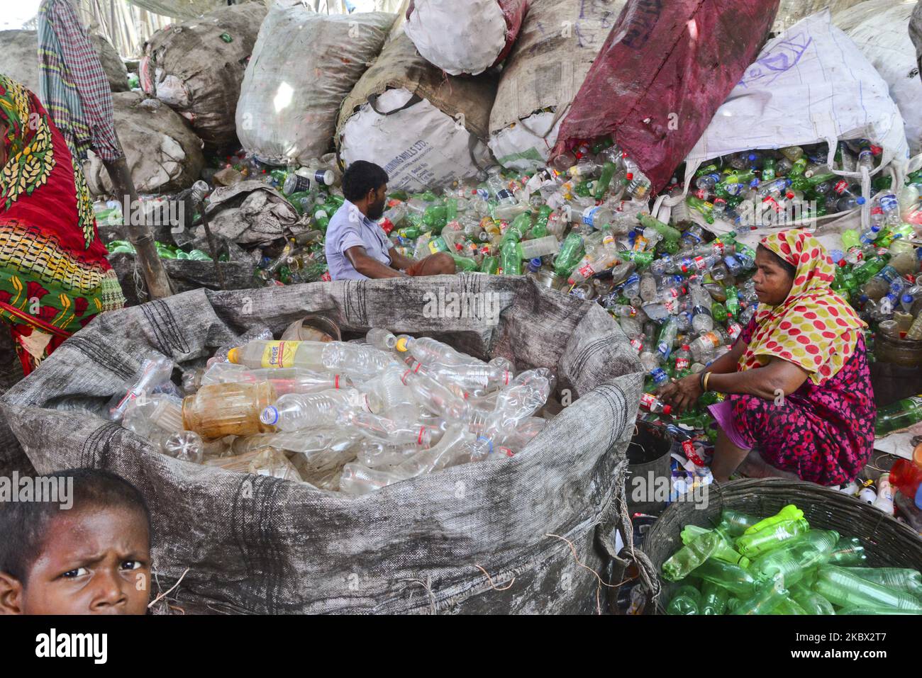Le lavoratrici della donna ordinano le bottiglie di polietilentereftalato (PET) in una fabbrica di riciclaggio a Dhaka, Bangladesh, il 12 agosto 2020. Negli ultimi due anni il riciclaggio delle bottiglie di plastica è diventato un'attività in crescita e contribuisce alla tutela dell'ambiente. Secondo la BPFMEA (Bangladesh PET Flakes Manufacturers and Exporters Association), il Bangladesh esporta in media circa 30.000 tonnellate di scaglie di PET in bottiglia principalmente verso Cina, Corea del Sud e Taiwan per un valore di $14 milioni di dollari l'anno. (Foto di Mamunur Rashid/NurPhoto) Foto Stock