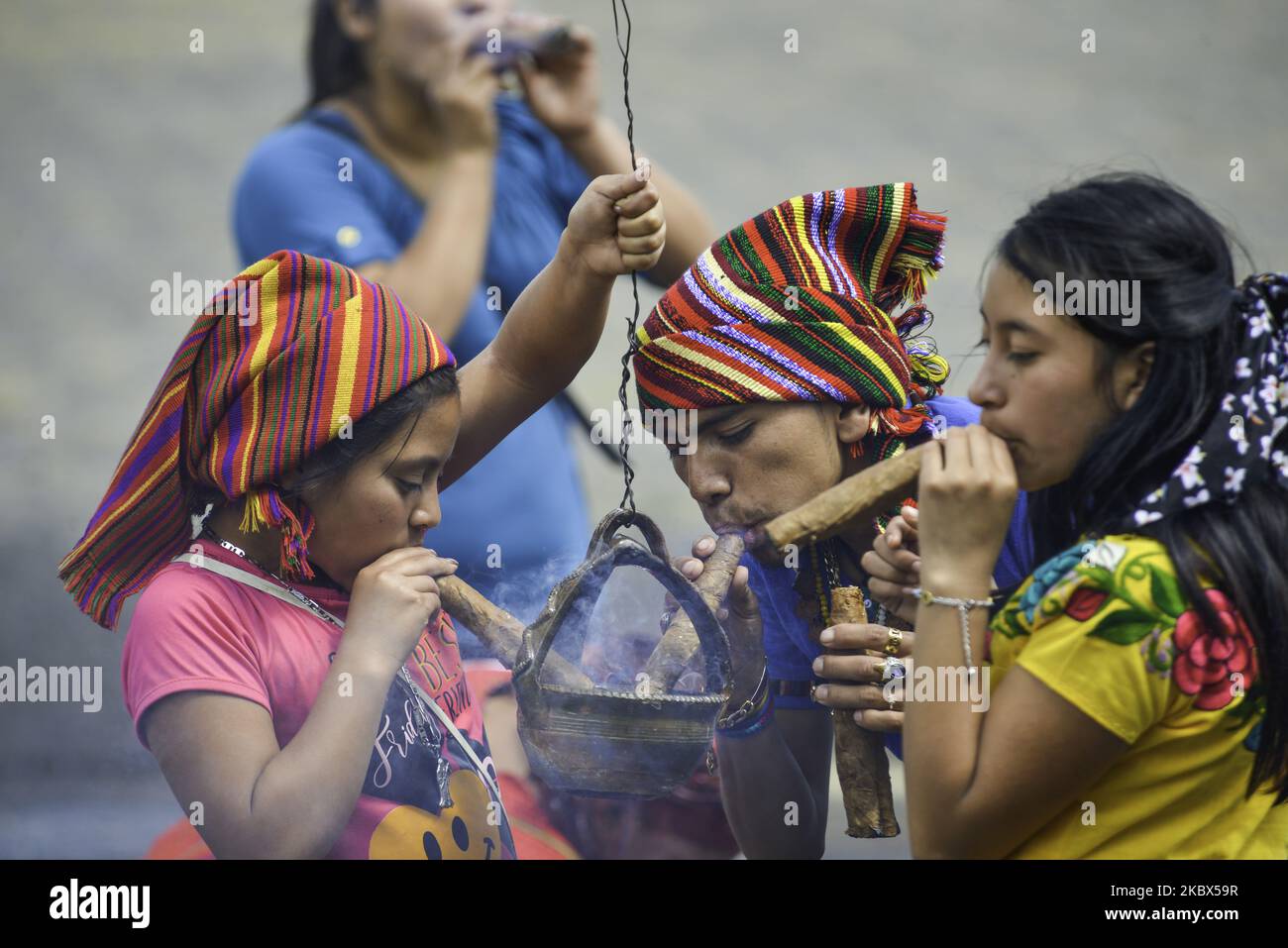 Una famiglia indigena fuma un sigaro fuori dal tempio durante la cerimonia a San Simone nel tempio di San Andrés Itzapa, 50 chilometri a ovest di Città del Guatemala, il 14 agosto 2020. Migliaia di persone credono che il santo che aiuta le persone a trovare lavoro, risolve i problemi familiari e cura le malattie. Durante la pandemia, il tempio fu chiuso per prevenire il contagio, con un totale di 61.428 persone infette e 2.341 morti in tutto il paese. (Foto di Deccio Serrano/NurPhoto) Foto Stock