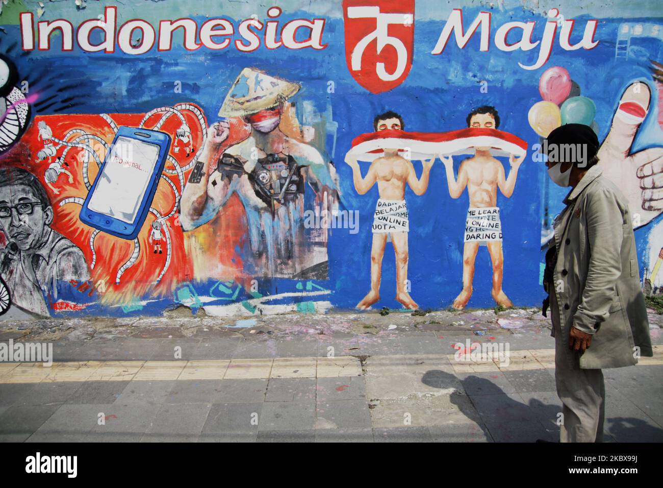 Bambang si trova di fronte al murale a tema dell'Indipendenza dipinto da lui e dagli amici sulla parete della strada accanto al suo studio di pittura di strada durante la celebrazione del 75th° giorno dell'Indipendenza dell'Indonesia a Giacarta, Indonesia, il 17 agosto 2020. Bambang Tridoyo (63), artista di pittura di strada. Ha iniziato la sua carriera dal 1975. In qualità di ammiratore del Padre fondatore dell'Indonesia, Sukarno, molte delle opere di Bambang sono ispirate da storie e figure eroiche. Non solo vendendo i suoi dipinti, accetta anche i servizi di pittura ritratto per i suoi clienti. La pandemia di Covid-19 che ha colpito l'Indonesia dalla fine di febbraio Foto Stock