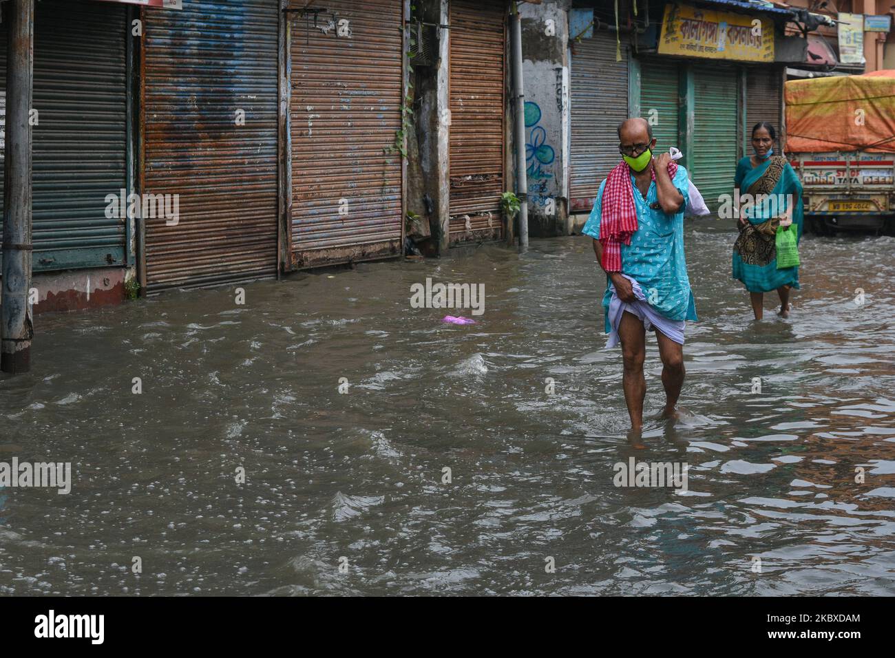 Un uomo che indossa una maschera cammina attraverso la strada più allagata di Kalighat, Kolkata, India, il 22 agosto 2020. La parte meridionale di Kolkata è stata colpita da un'alluvione lampo durante l'alta marea su Gange nel sabato pomeriggio. La città è martoriata da una forte pioggia da un paio di giorni, causando il fiume a traboccare durante l'alta marea. La stragrande maggioranza delle basse zone di Kolkata del Sud ha ottenuto l'acqua registrata a causa dell'alluvione flash. (Foto di Debarchan Chatterjee/NurPhoto) Foto Stock