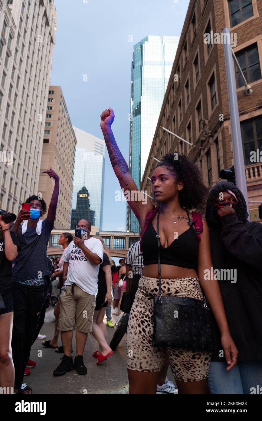 Un manifestante solleva il pugno in disfienza mentre le tensioni si flano nel centro di Minneapolis, Stati Uniti il 26 agosto 2020 a seguito di voci di una polizia che spara in centro. I residenti hanno protestato nel centro di Minneapolis il 26 agosto dopo che sono circolate notizie imprecise di un uomo colpito dalla polizia. Dopo una tensione di stand-off tra ufficiali e manifestanti, più negozi sono stati saccheggiati. Decine di persone sono state arrestate, un coprifuoco è stato imposto poco dopo le 10, e il governatore Walz ha dichiarato lo stato di emergenza, chiedendo in forma di sostegno la Guardia Nazionale. (Foto di Tim Evans/NurPhoto) Foto Stock