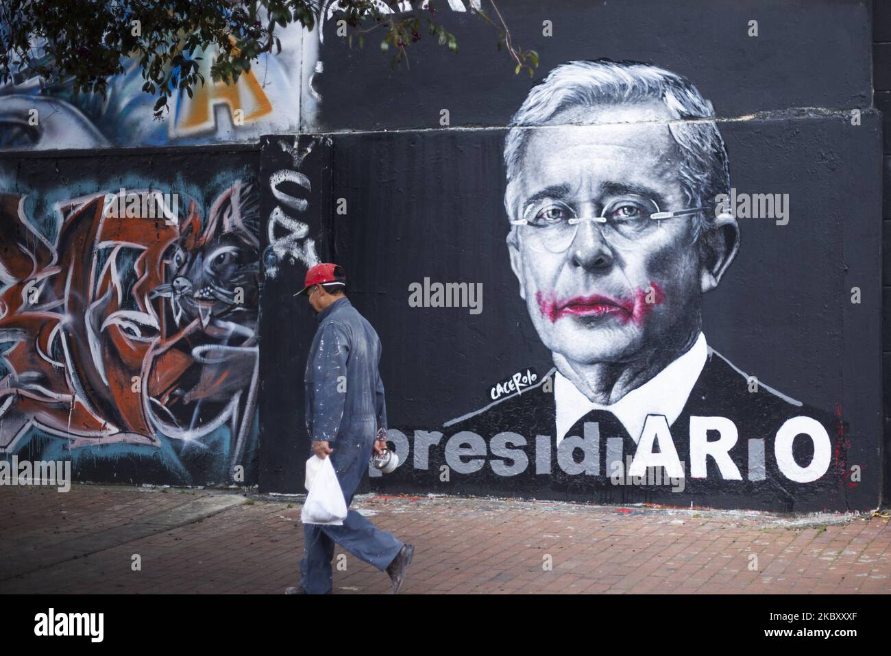 Una persona cammina accanto all'immagine dell'ex presidente Alvaro Uribe Velez, il 31 agosto 2020 a Bogotà, Colombia. Qualche settimana fa è stato detenuto agli arresti domiciliari accusato di frode e di manomissione di testimoni. (Foto di Daniel Garzon Herazo/NurPhoto) Foto Stock