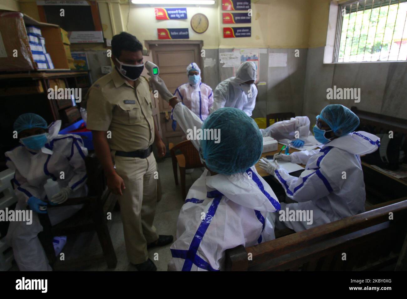 Un operatore sanitario che indossa dispositivi di protezione individuale  (DPI) controlla la temperatura di un agente di polizia all'interno della  struttura di test Rapid Antigen Covid-19 a Mumbai, India, il 02 settembre