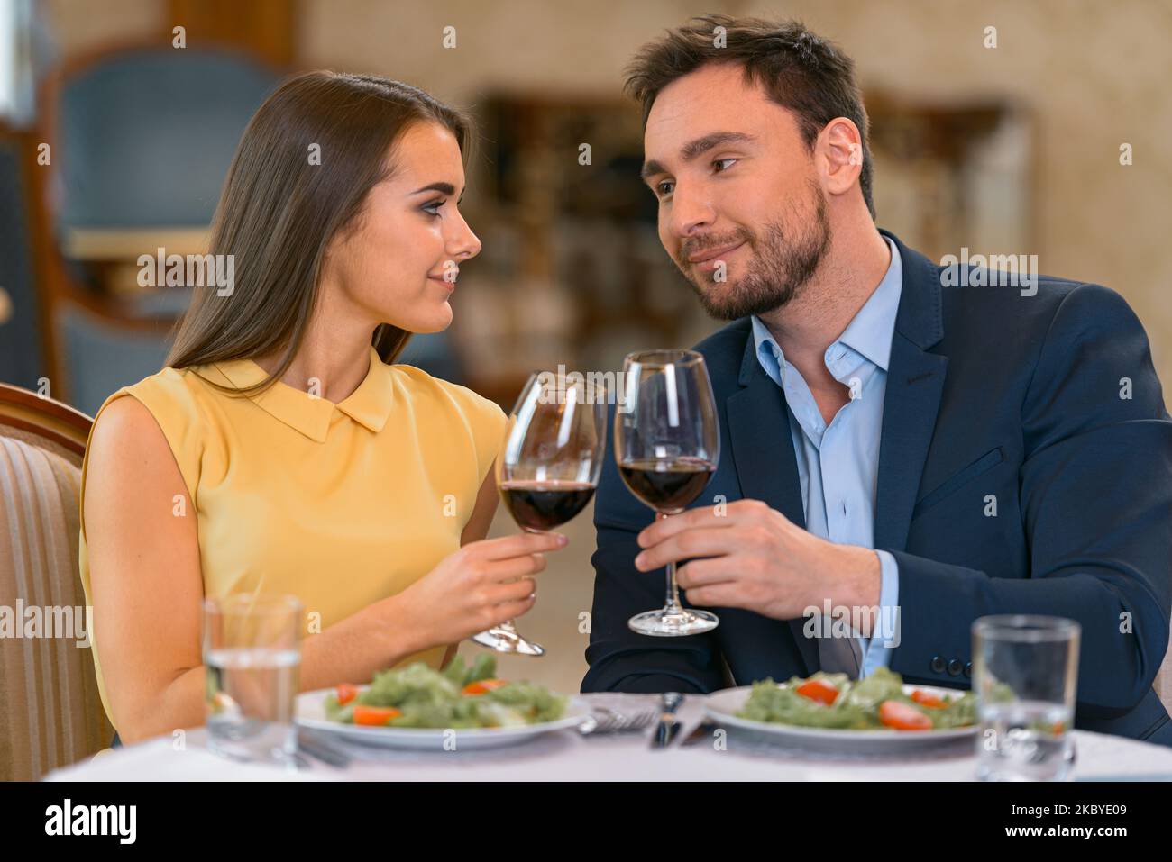 Bella giovane coppia con bicchieri di vino in un appuntamento romantico in un ristorante di lusso Foto Stock