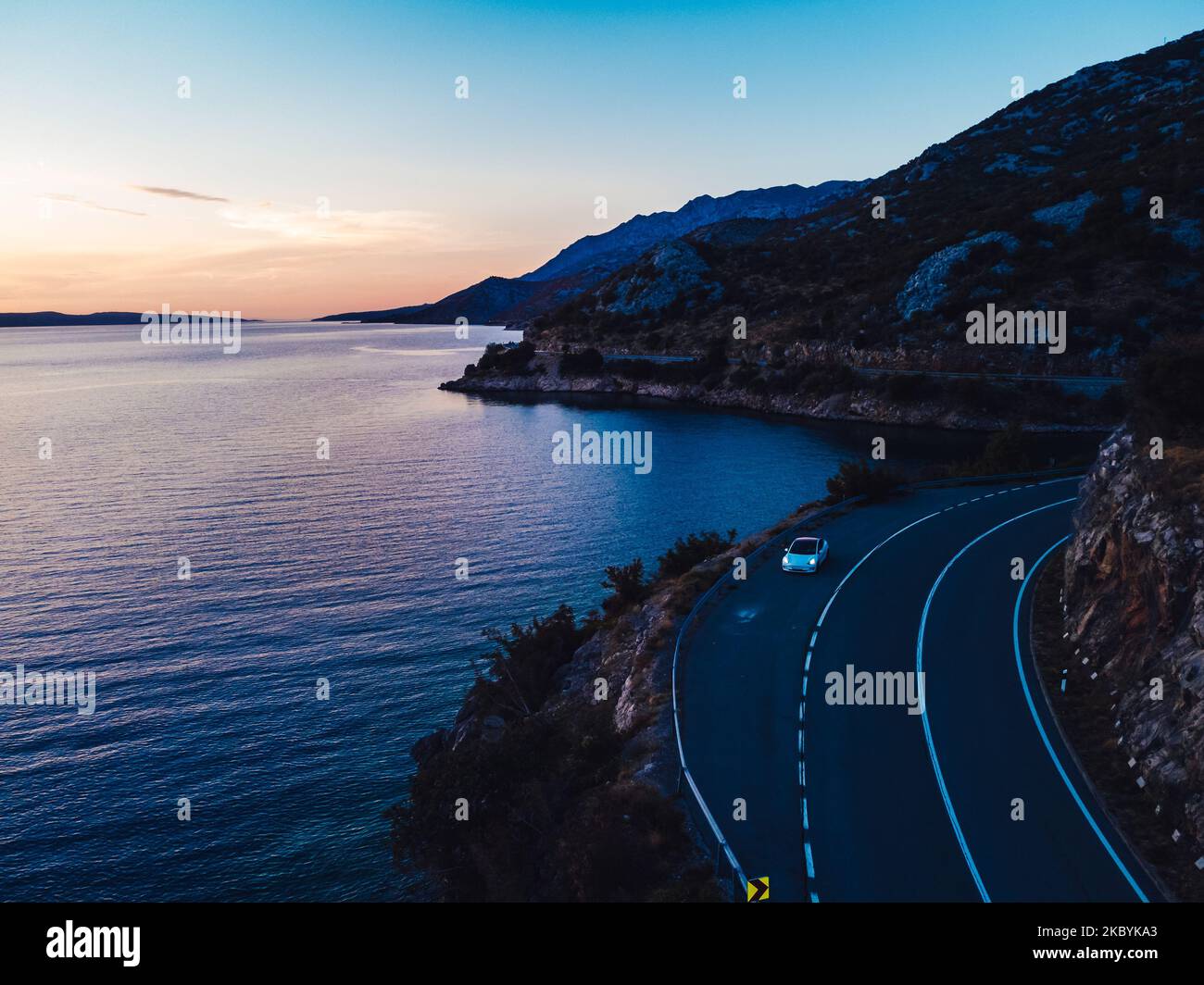 Una bella vista al tramonto di un'auto sulla strada accanto al mare in Croazia. Perfetto per lo sfondo Foto Stock