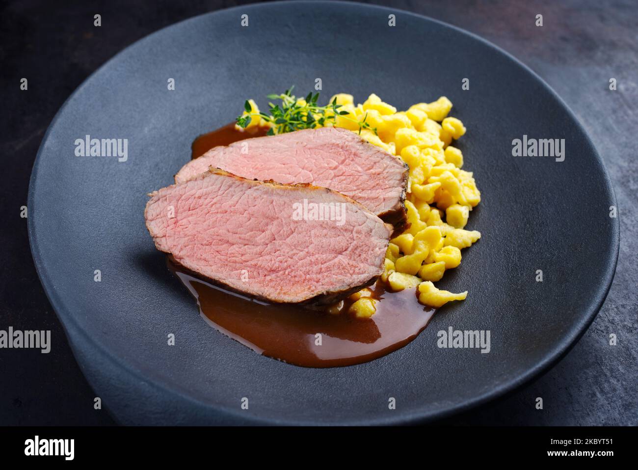 Fettine di vitello arrosto Tafelspitz con spaetzle sveva servite con salsa di birra scura come primo piano in un piatto di design Foto Stock