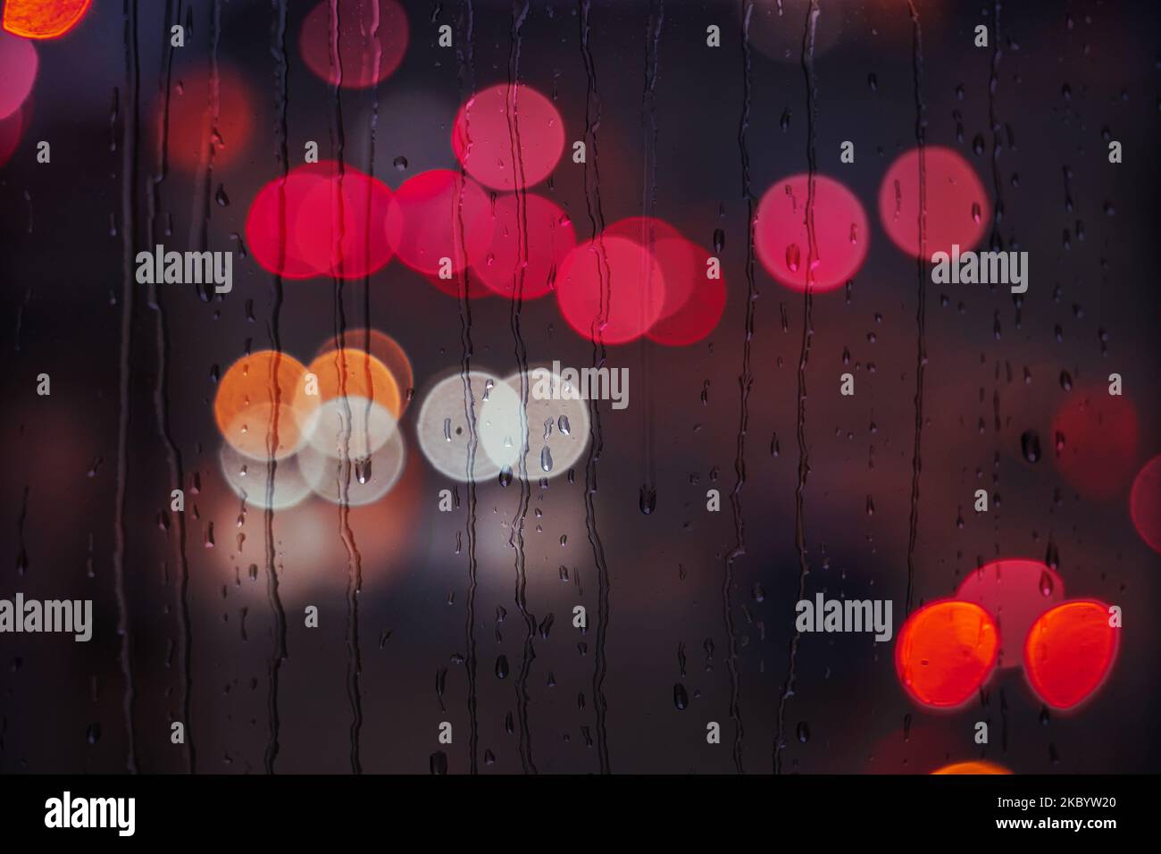 gocce di pioggia sulla finestra nei giorni piovosi e le luci della strada sfondo Foto Stock