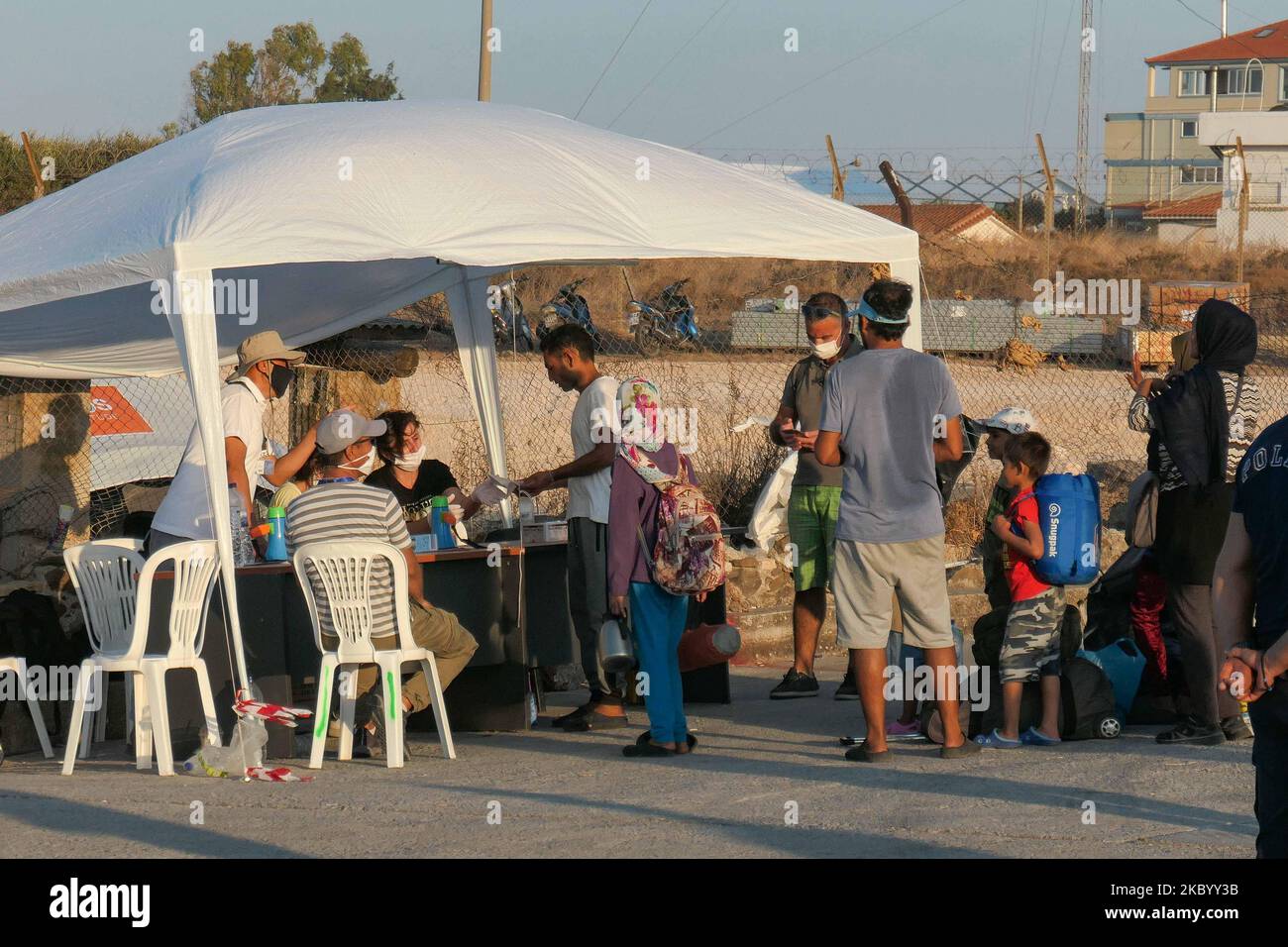 Le famiglie di migranti provenienti dall'Afghanistan sono viste in attesa in fila, si registrano, hanno un test rapido Coronavirus Covid-19 ed entrano nel nuovo campo profughi dell'isola di Lesbos, Grecia dopo il grande incendio che ha distrutto completamente il campo di Moria, prima accoglienza e registrazione campo profughi sull'isola. Il nuovo campo vicino alla capitale dell'isola Mytilene a Mavrovouni o Kara Tepe è un ex campo di tiro militare pratica, ma i migranti sono scettici di entrare in quanto è una struttura chiusa per il momento che non permetterà loro di vagare liberamente, nonostante il fatto che il cibo, tende, servizi igienici e m Foto Stock