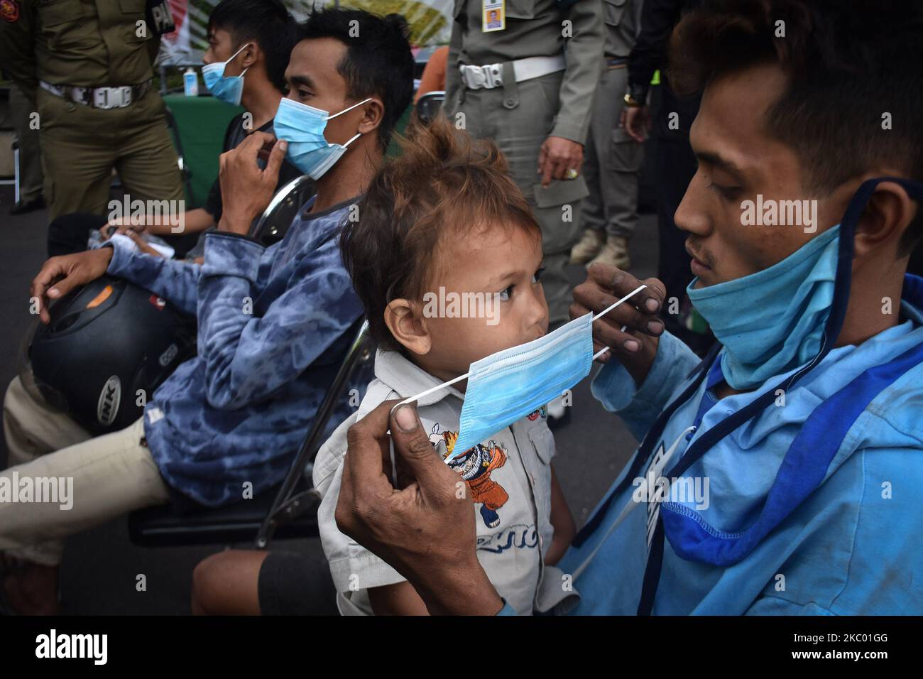 Un bambino indossa una maschera dal padre in attesa di un processo per la violazione dei protocolli sanitari. Perché non indossare una maschera durante il periodo Covid-19 con una multa massima di Rp 100.000 ($ 6,72) a persona o 3 giorni di carcere a Malang, Giava Est, Indonesia, 16 settembre 2020. Il governo indonesiano continua a lottare per ridurre il numero di persone esposte positivamente al focolaio della corona-19, che ha più di 228 mila persone e che ha raggiunto i 9 mila il 16 settembre. La sua influenza sulla minaccia di una recessione economica. (Foto di Aman Rochman/NurPhoto) Foto Stock