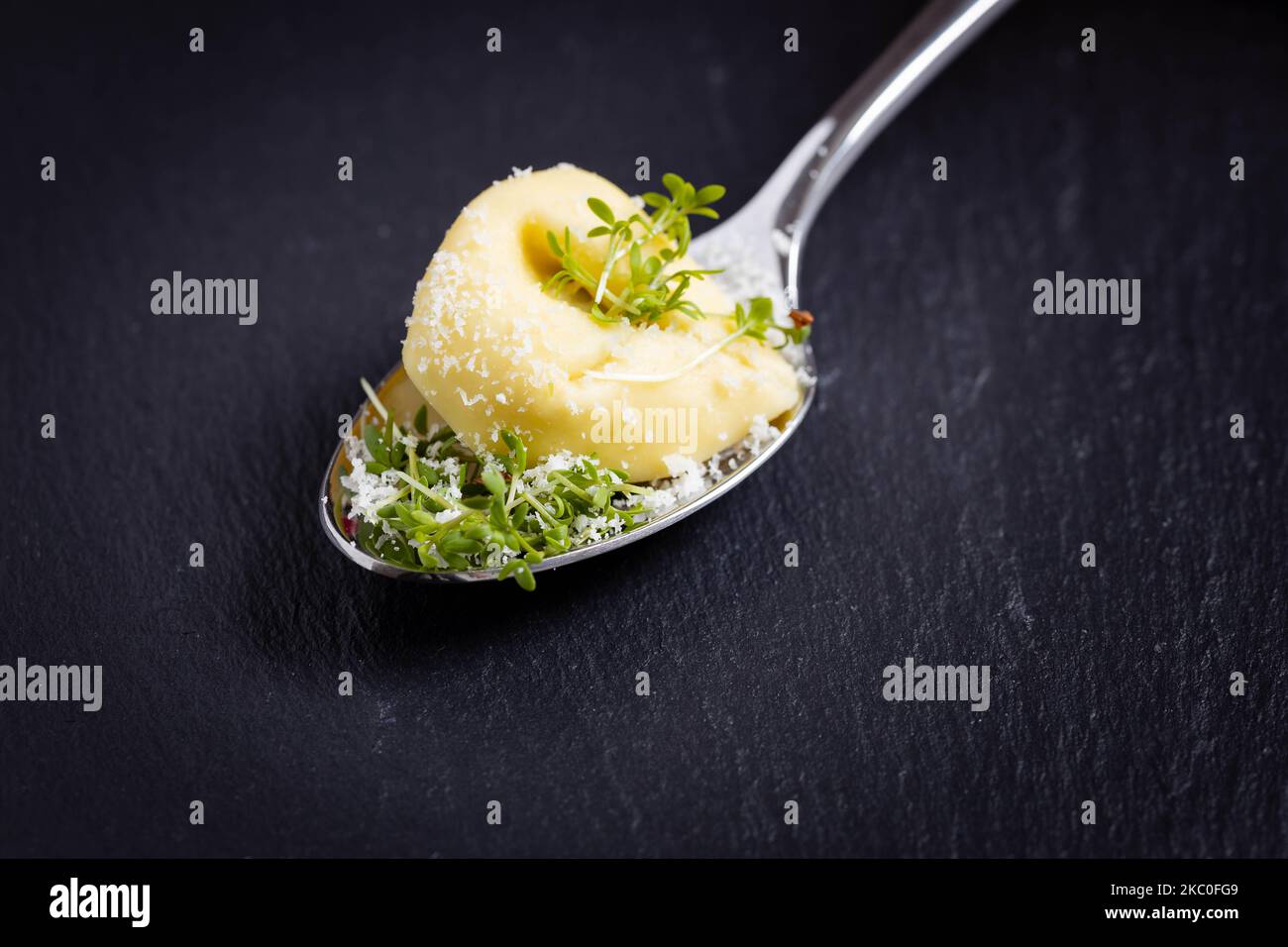 tortellini su un cucchiaio su sfondo nero, fotografati dal davanti Foto Stock