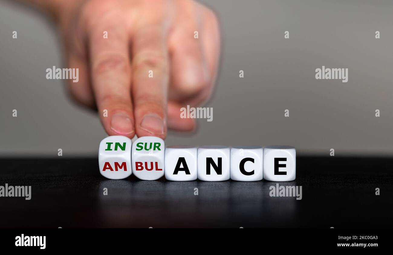 La mano gira i dadi e cambia la parola ambulanza in assicurazione. Foto Stock