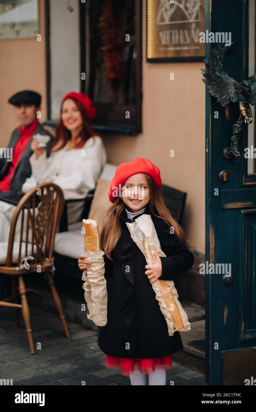 Una ragazza alla moda con baguette si trova vicino al negozio sullo sfondo dei suoi genitori Foto Stock