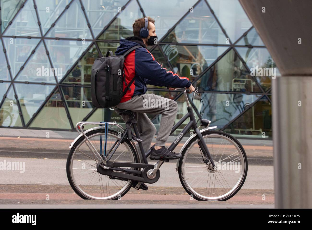 Vita quotidiana nella città di Eindhoven nei Paesi Bassi con persone che indossano il facemask come fuori a piedi o in bicicletta come misura protettiva contro la diffusione della pandemia di Coronavirus Covid-19. Martedì 13 ottobre 2020 il primo ministro olandese Mark Rutte ha annunciato che i Paesi Bassi devono tornare ad un blocco parziale, chiudendo i bar e i ristoranti, l'uso obbligatorio della maschera facciale al chiuso, la limitazione al numero di persone che si riuniscono al chiuso, le attività sportive e altro ancora sono interessati. Il paese è stato uno dei principali focolai in Europa. Eindhoven, Paesi Bassi il Martedì 13 Foto Stock