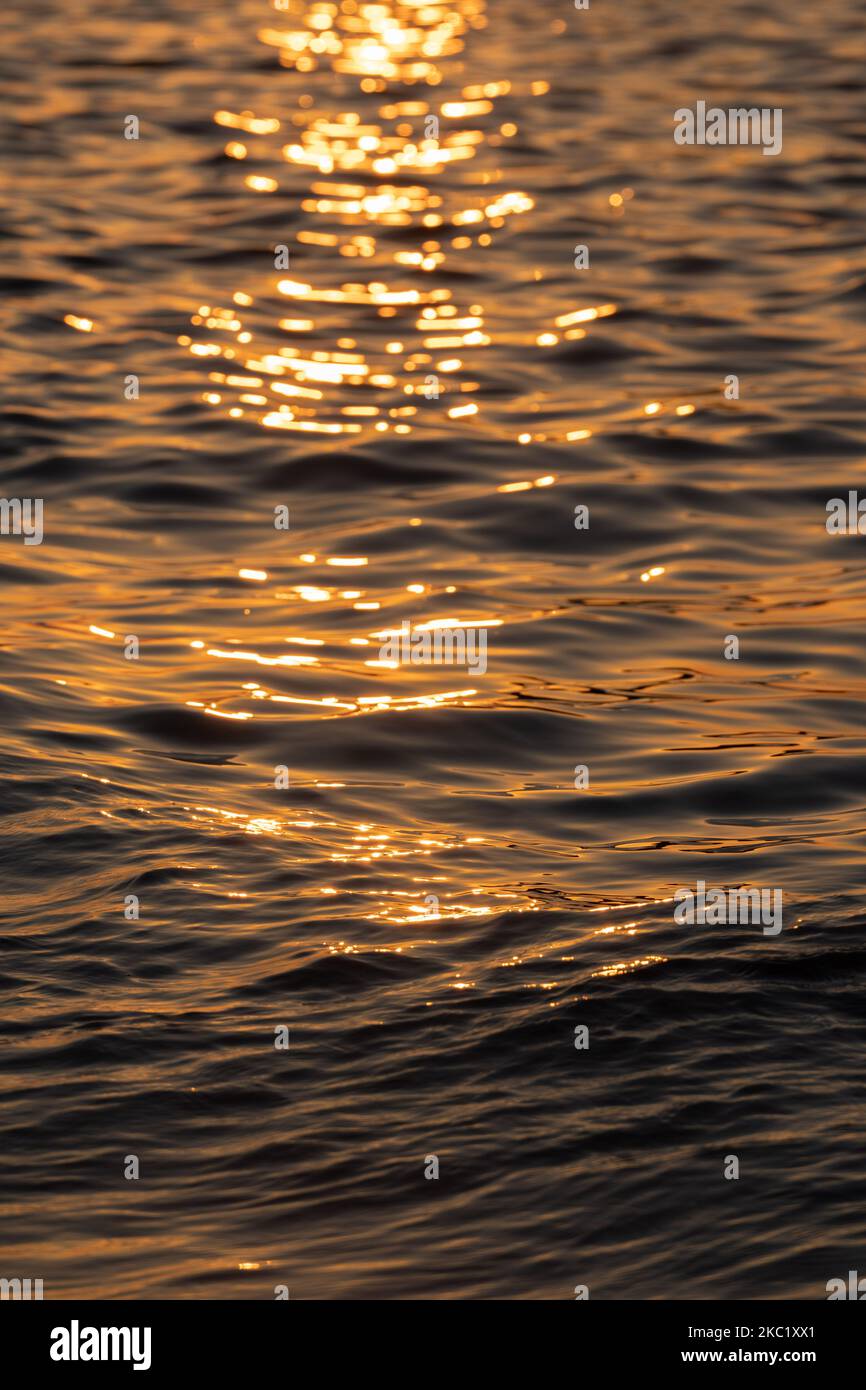 Ripple acqua mare oceano superficie con luce tramonto dorato. Primo piano dell'onda di mare Foto Stock