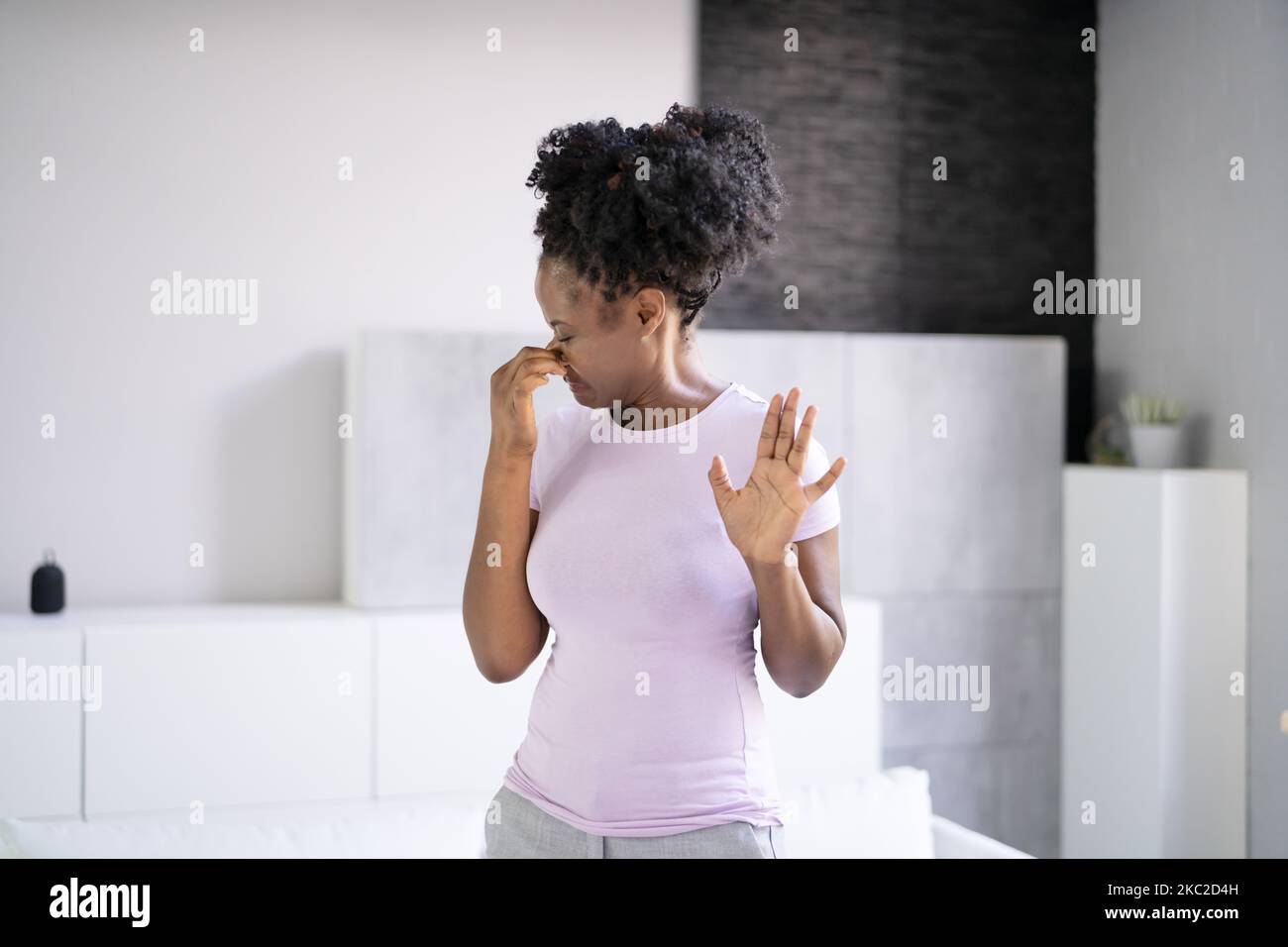 Donna africana che sente cattivo odore di aria o Odor in casa Foto Stock