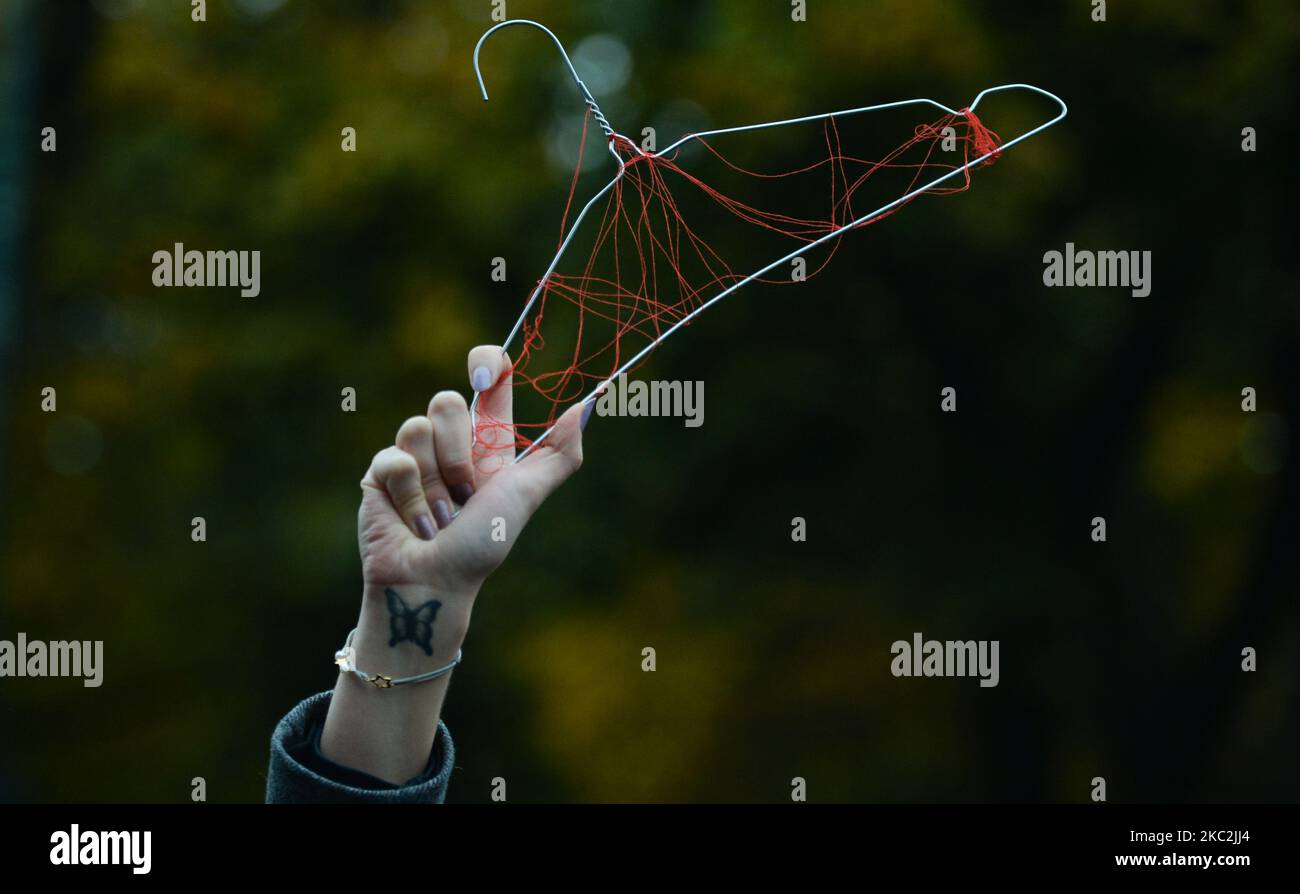 Un attivista tiene un appendiabiti che simboleggia l'aborto illegale e non sicuro. Migliaia di persone di tutte le età hanno marciato di nuovo a Cracovia e in altre città polacche per il quarto giorno di fila in una serie di proteste contro la nuova legge sull'aborto. La protesta è una reazione diretta alla sentenza di giovedì della Corte Suprema polacca secondo cui la legge esistente che autorizza la cessazione della gravidanza per il feto è contraria alla costituzione, inasprendo di fatto uno dei più severi regimi di aborto in Europa. Domenica 25 ottobre 2020 a Cracovia, Polonia. (Foto di Artur Widak/NurPhoto) Foto Stock