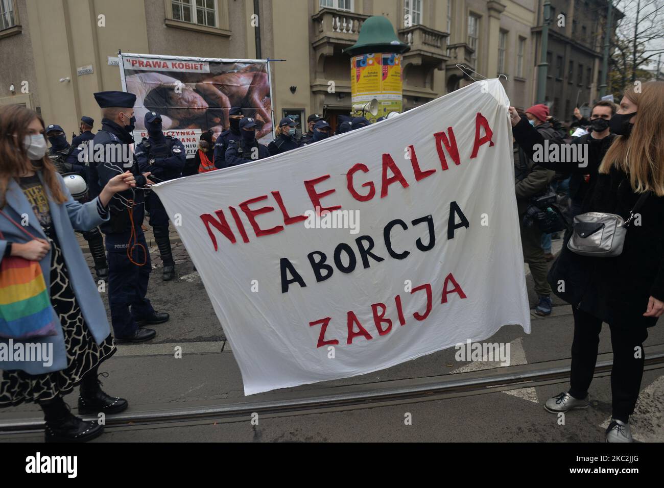 I manifestanti pro-choice hanno il banner "l'aborto illegale uccide" durante la manifestazione, mentre passano davanti a un piccolo gruppo di anti-dimostranti Pro-Life. Migliaia di persone di tutte le età hanno marciato di nuovo a Cracovia e in altre città polacche per il quarto giorno di fila in una serie di proteste contro la nuova legge sull'aborto. La protesta è una reazione diretta alla sentenza di giovedì della Corte Suprema polacca secondo cui la legge esistente che autorizza la cessazione della gravidanza per il feto è contraria alla costituzione, inasprendo di fatto uno dei più severi regimi di aborto in Europa. Domenica 25 ottobre 2020 a Cracovia, Polonia. Foto Stock
