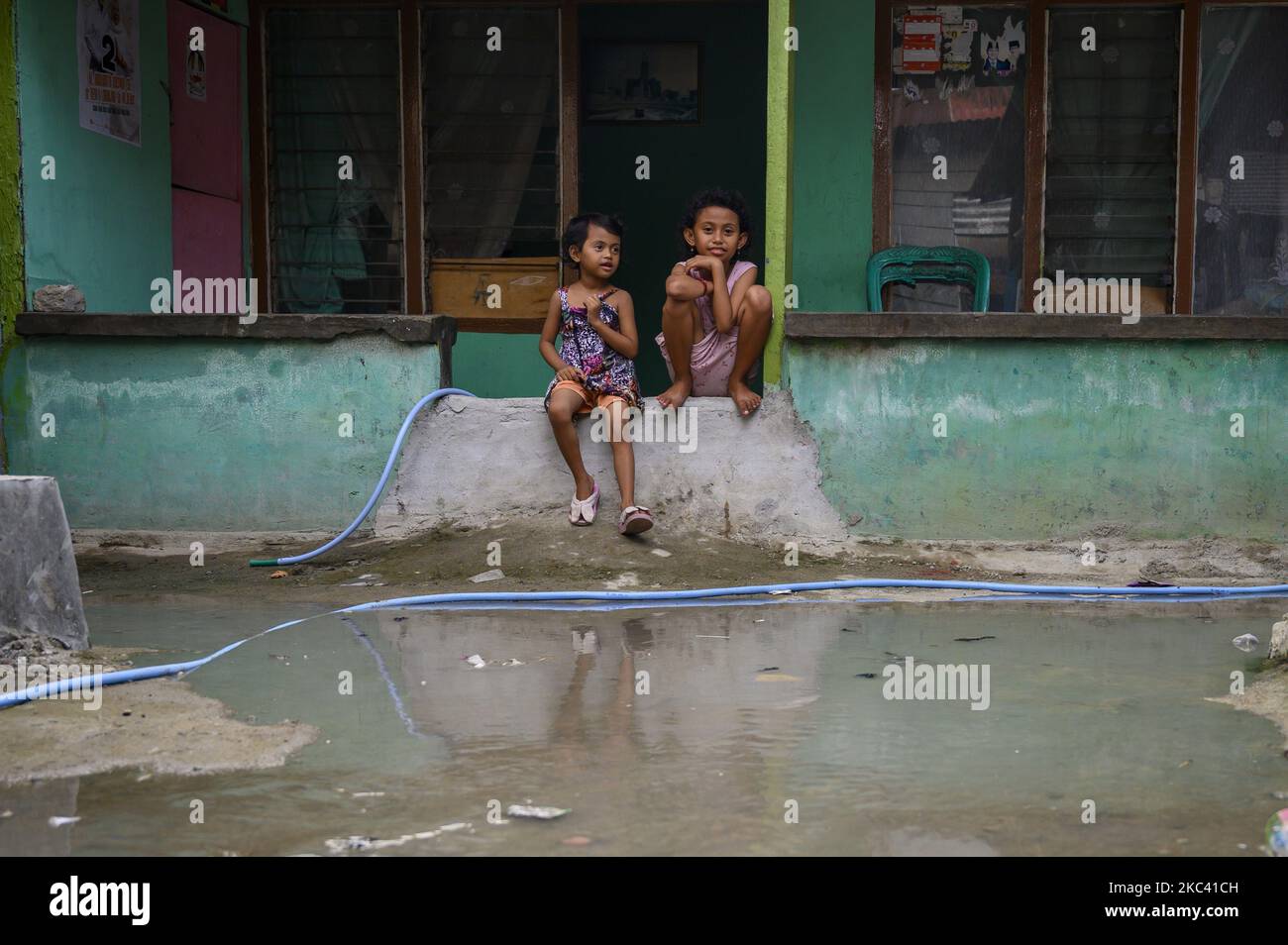 Due bambini si sedettero di fronte alla loro casa quando l'acqua cominciò ad inarsi a causa delle alluvioni nel villaggio di Lere, Palu, nella Provincia Centrale di Sulawesi, Indonesia, il 14 novembre 2020. Oltre ad essere causato da alte maree, alluvioni che si verificano per cinque giorni ogni mese, è anche causato da subsidence di terra fino a 1,5 metri a causa del terremoto di magnitudo 7,4 due anni fa sulla costa di Palu Bay. Il terremoto che ha scatenato lo tsunami e la liquefazione ha ucciso più di 5.000 residenti. (Foto di Basri Marzuki/NurPhoto) Foto Stock