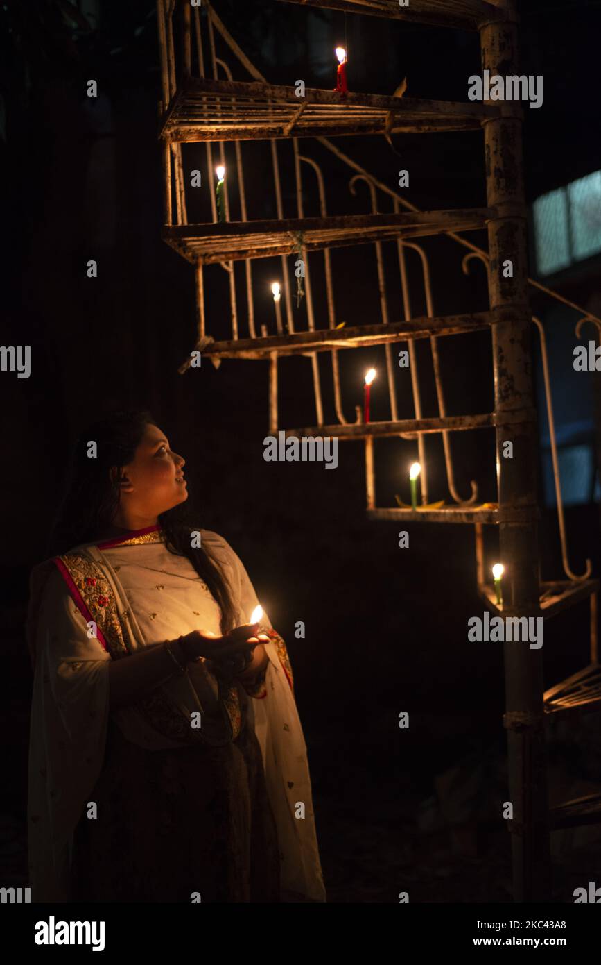 Una ragazza che tiene una lampada ad olio accanto alle scale fuori casa mentre celebra Diwali a Narayanganj, Bangladesh il 15 novembre 2020. (Foto di Ziaul Haque/NurPhoto) Foto Stock