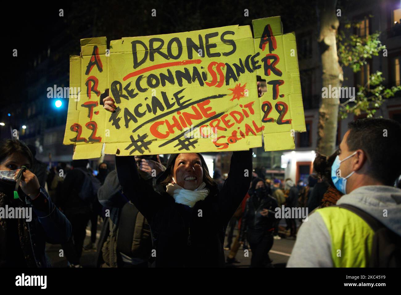 Una donna brandisce un cartoncino che legge 'droni, riconoscimento facciale uguale Cina e credito sociale'. Diverse ONG (Amnesty International, Human Rights League), sindacati (CGT, CNT, CFDT, SAF vale a dire l'Unione degli avvocati francesi), i sindacati dei giornalisti (SNJ, SNJ-CGT), la Federazione internazionale ed europea dei giornalisti, e i partiti politici hanno chiesto un incontro contro il cosiddetto disegno di legge "Global Security Law" promosso dal presidente francese Macron e dalla sua maggioranza. Il raduno si è concluso tra le nubi di gas lacrimogeno lanciate dalla polizia antisommossa. Questa legge intende conferire maggiori poteri alla polizia municipale e a quella privata Foto Stock