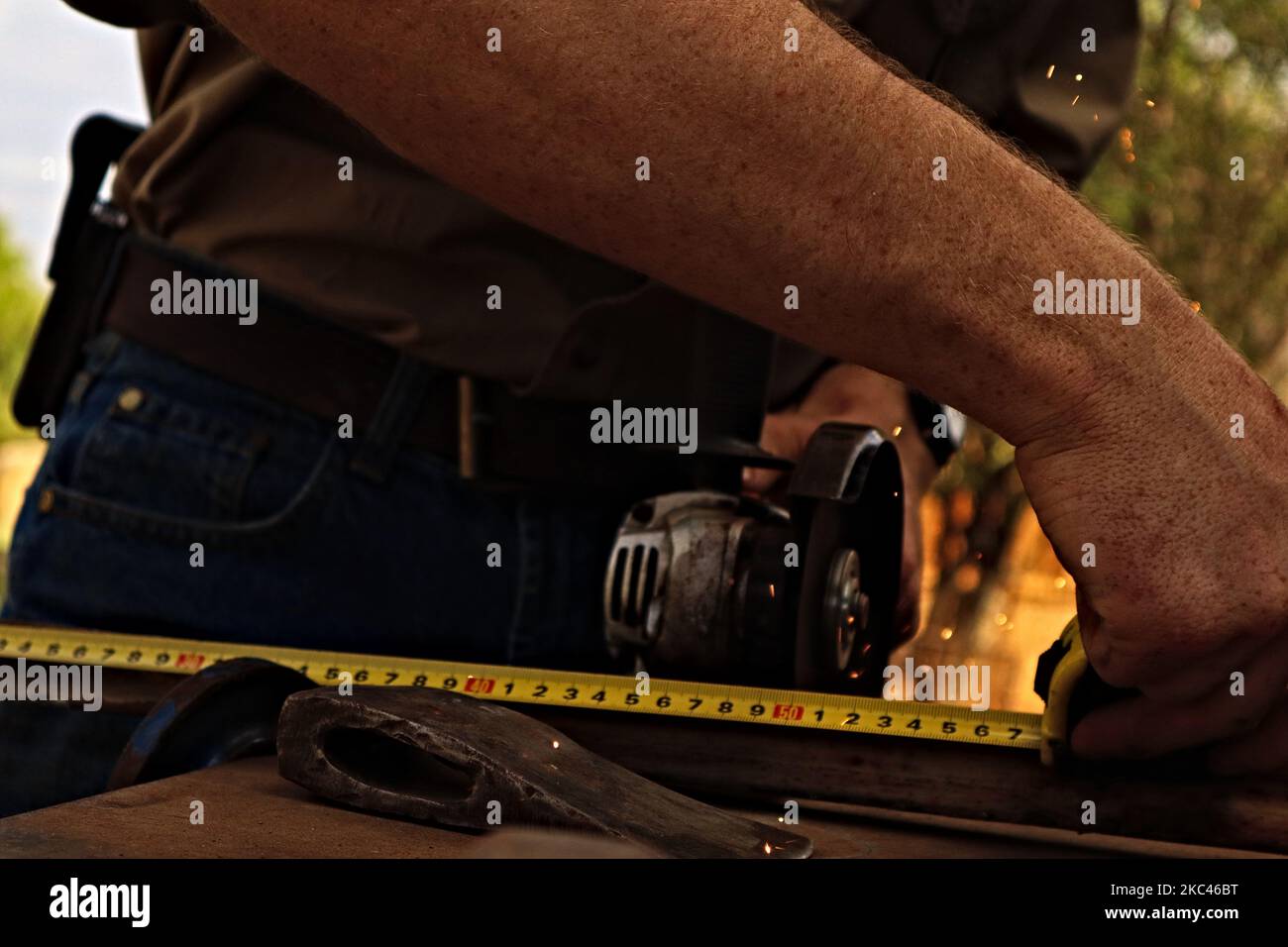 Un uomo che misura le particelle metalliche con il nastro prima di tagliare, primo piano Foto Stock