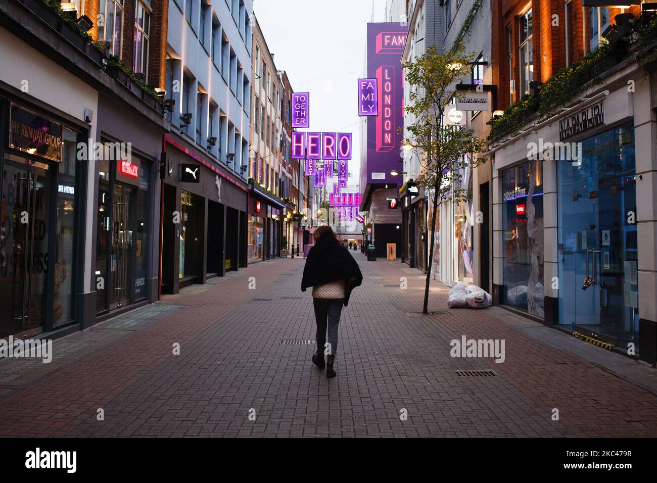 Una donna cammina lungo una vicina Carnaby Street a Londra, Inghilterra, il 18 novembre 2020. In tutta l'Inghilterra negozi non essenziali, bar, ristoranti e altre aziende del settore alberghiero rimangono chiusi come parte del secondo blocco nazionale del coronavirus, iniziato il 5 novembre e in scadenza il 2 dicembre. Il primo ministro britannico Boris Johnson, che ha indicato di non voler estendere il blocco, nel frattempo rimane in isolamento a Downing Street dopo essere venuto in contatto con un deputato giovedì scorso che ha poi testato positivo per il covid-19. Il primo ministro himse Foto Stock