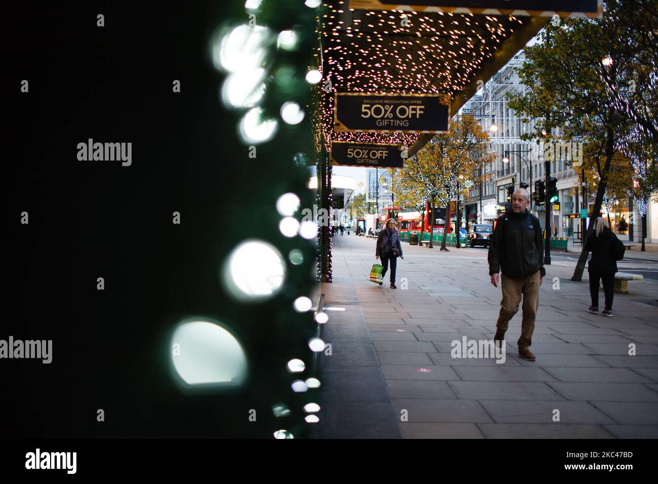 La gente passa davanti alle luci di Natale su una tranquilla Oxford Street a Londra, Inghilterra, il 18 novembre 2020. In tutta l'Inghilterra negozi non essenziali, bar, ristoranti e altre aziende del settore alberghiero rimangono chiusi come parte del secondo blocco nazionale del coronavirus, iniziato il 5 novembre e in scadenza il 2 dicembre. Il primo ministro britannico Boris Johnson, che ha indicato di non voler estendere il blocco, nel frattempo rimane in isolamento a Downing Street dopo essere venuto in contatto con un deputato giovedì scorso che ha poi testato positivo per il covid-19. Il primo minista Foto Stock